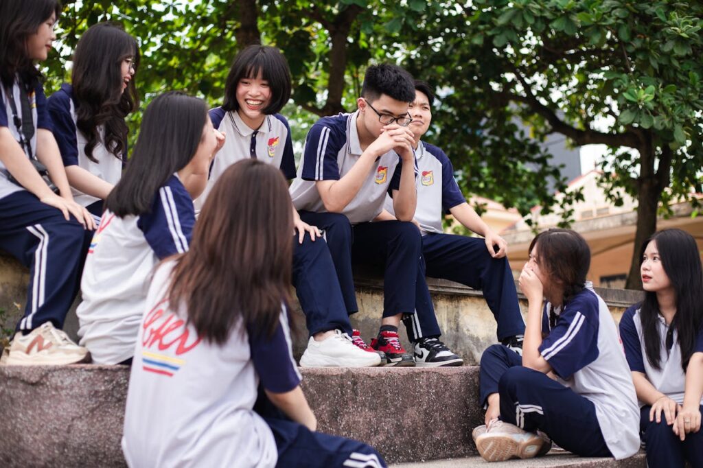 A group of Vietnamese students in school uniforms enjoying a casual outdoor gathering at their campus.